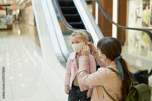 Mom puts a protective mask on a child in a shopping center