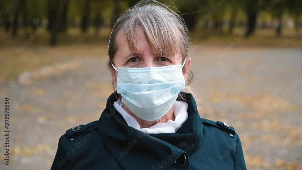 Close up portrait of a Senior woman with sad eyes in a Medical protection mask is looks seriously. Quarantine coronavirus covid-19 for old people. Retirement Health at Risk, granny in mask. Concept of Close up portrait of a Senior woman with sad eyes in a Medical protection mask is looks seriously. Quarantine coronavirus covid-19 for old people. Retirement Health at Risk, granny in mask. Concept of