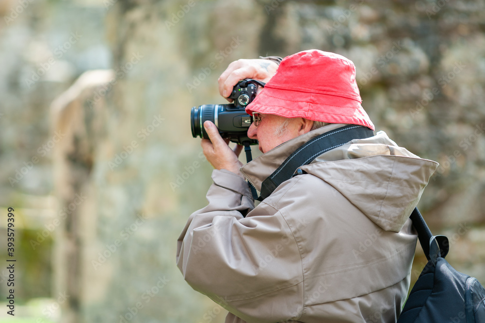 An elderly man uses a camera in ancient ruins