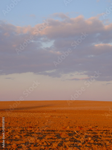 Cloudy evening sky over an empty agricultural field. Bright sunset landscape.