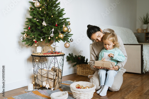 Mom and daughter decorate the Christmas tree in room.  Merry christmas and happy new year concept. Space for text. Family cozy moments. photo