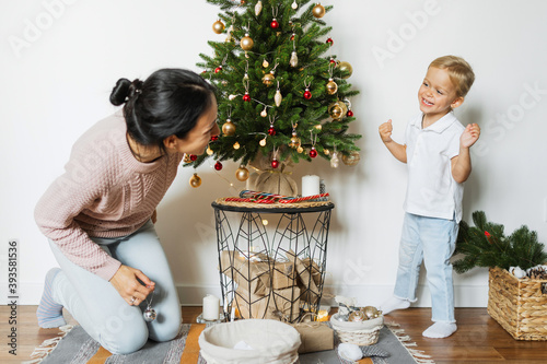 Mom and daughter decorate the Christmas tree in room.  Merry christmas and happy new year concept. Space for text. Family cozy moments. photo