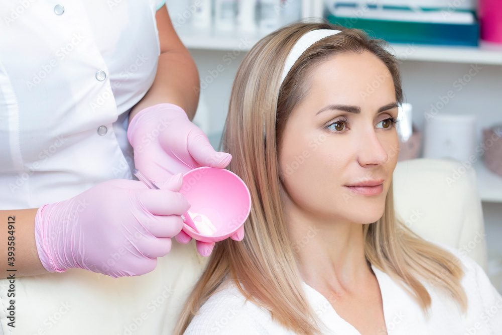 Fototapeta premium cosmetology. young woman with receiving facial cleansing procedure in beauty salon.