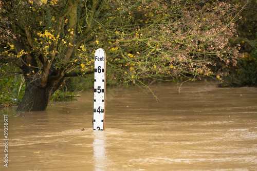 River gauge water level indicator in a flooded river at the ford in Much Hadham, Hertfordshire. UK