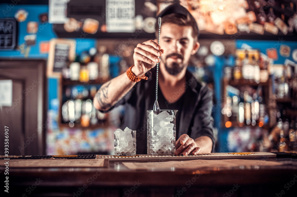 Focused bartending pouring fresh alcoholic drink into the glasses in pub