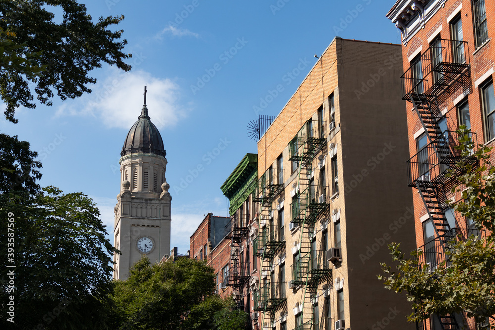 Church Steeple and Row of Colorful Old Residential Buildings with Fire Escapes in the East Village of New York City