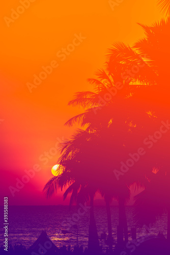Vertical image of silhouette coconut tree and beautiful sunset at beach of Thailand. Adjusted color design for vintage looks.