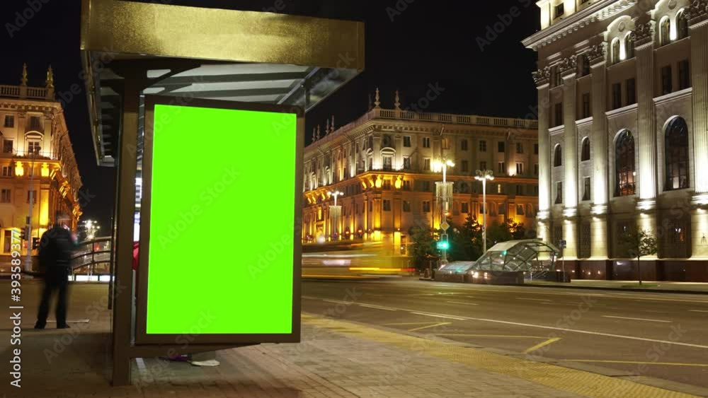 Billboard with a chroma key green screen on n bus stop at night. Time Lapse.