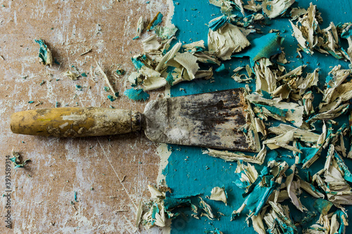 Restoration of an old door.Removing old paint coats with a heat gun and a spatula. View from above .Close-up. Spatula and pieces of curled blue paint.