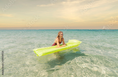 young woman in a one-piece swimsuit in the sea with an inflatable mattress