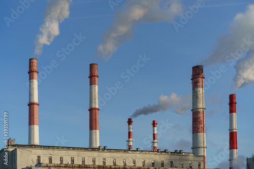 Heat station pipes, smoke. Smoking pipes, gray smoke with winter sky as background. Chimneys, concept of industry and ecology, heating season, global warming
