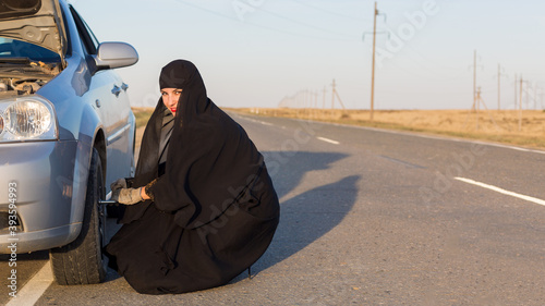 Muslim woman driver changes car wheel