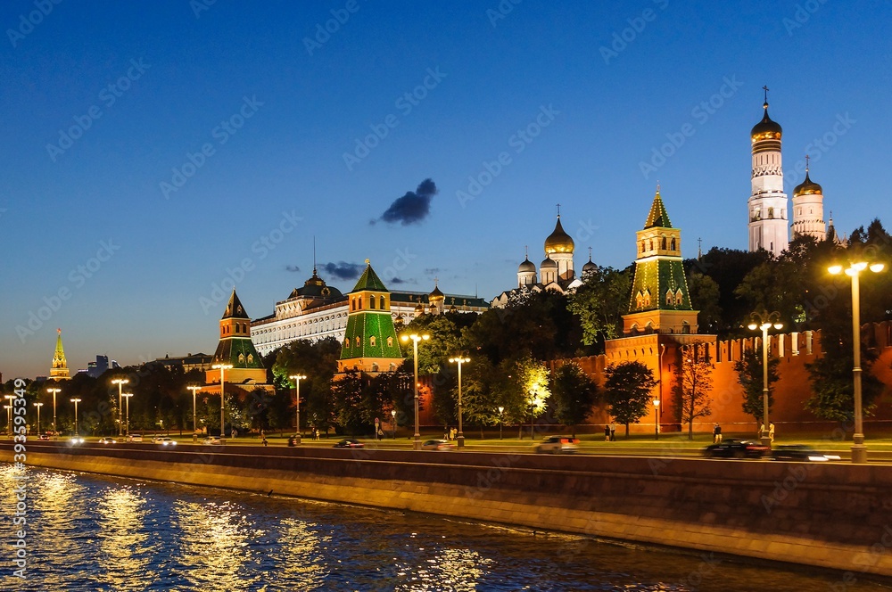 Obraz premium View of the Kremlin embankment, the towers of the Kremlin, the Grand Kremlin Palace, Ivan the Great Bell Tower in the late evening in August. Moscow, Russia