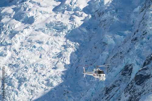 Helicopter coming in for landing on The Tasman Glacier (Haupapa) which is the largest glacier in the Southern Alps, South Island, New Zealand.  photo