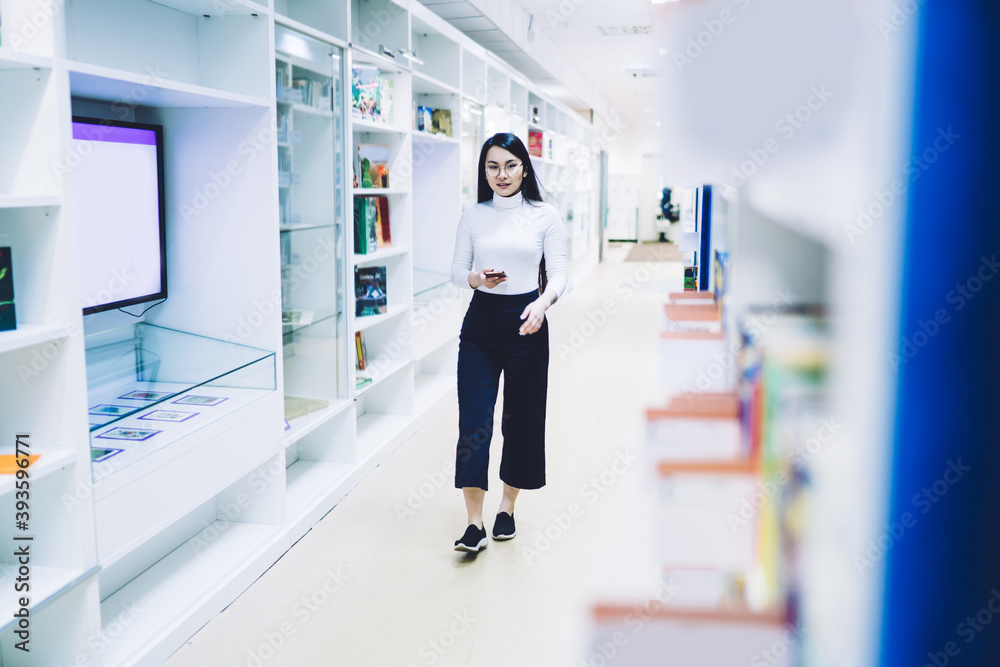 Young woman using smartphone and walking trough corridor
