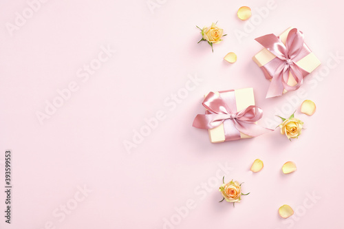 Gift boxes with pink ribbon bow and yellow roses flowers petals and buds on pastel pink background. Valentines day, Mothers day, birthday concept. Minimal style. © photoguns