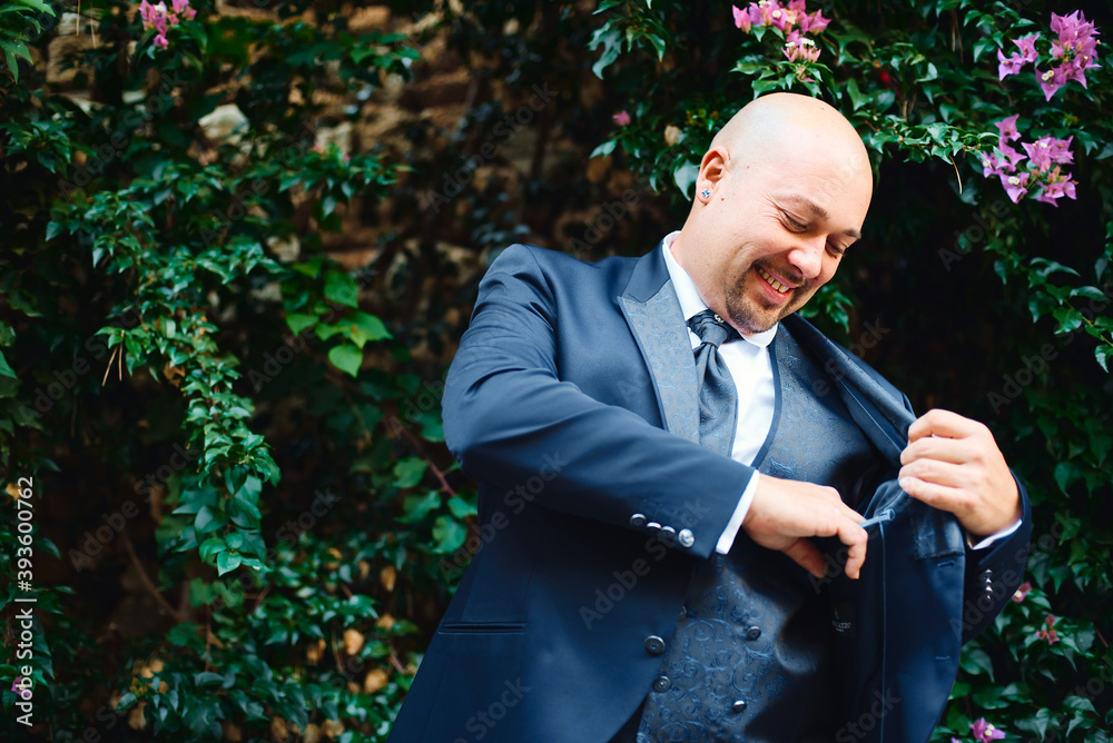 Portrait of the groom holding his jacket against the background of green bushes, wedding suit Portrait of the groom holding his jacket against the background of green bushes, wedding suit