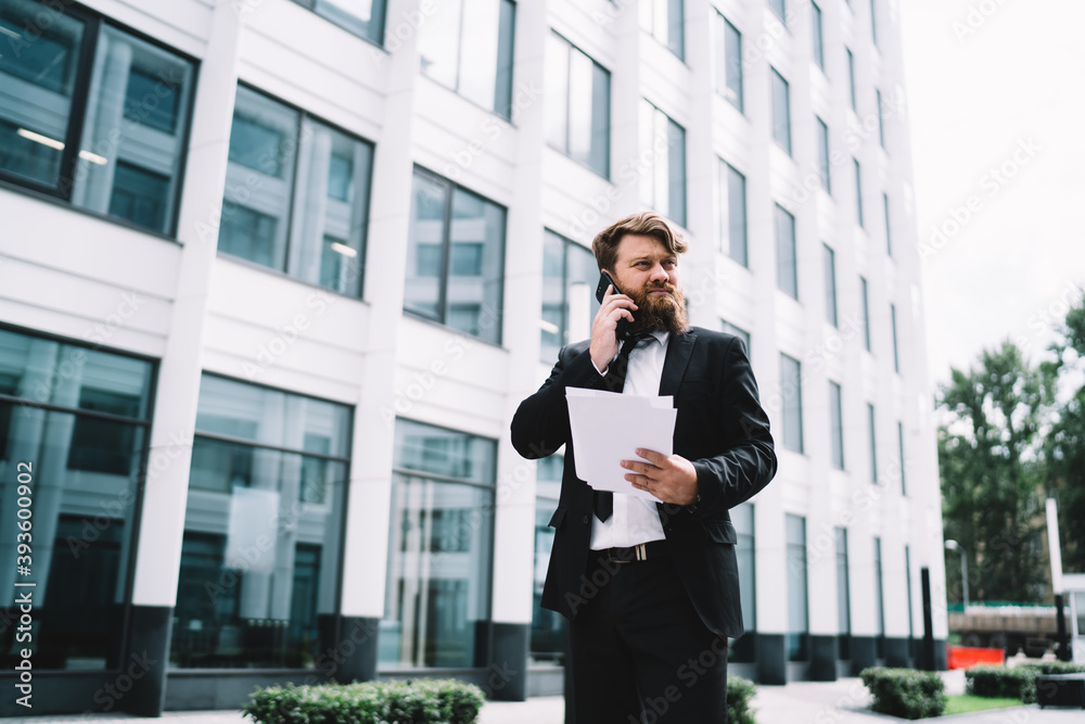 Serious businessman talking on cellphone standing Serious businessman talking on cellphone standing