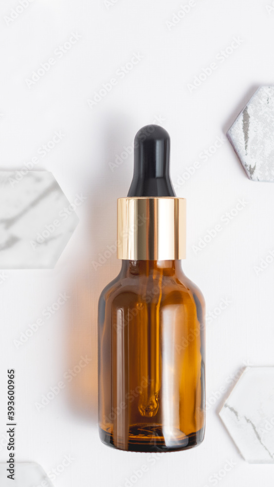 Top view on glass bottles of essential oil or cosmetic serum on white background. Decorative marble and glass hexagons. Top view on glass bottles of essential oil or cosmetic serum on white background. Decorative marble and glass hexagons.