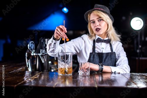 Focused girl bartending pouring fresh alcoholic drink into the glasses behind the bar photo