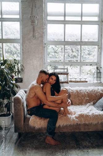 Romantic intimate photo session of a young couple. The guy and the girl spend time together. A love story in a cozy home environment.