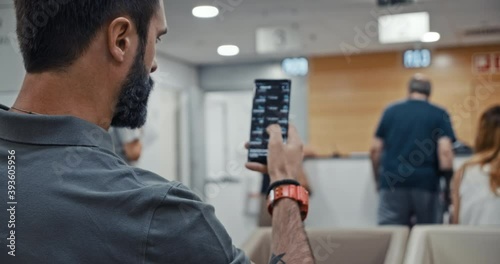 Bearded man using mobile phone while sitting at hospital lobby waiting doctor visit. Mobile technology user working in digital applications gadget searching information online, texting messages