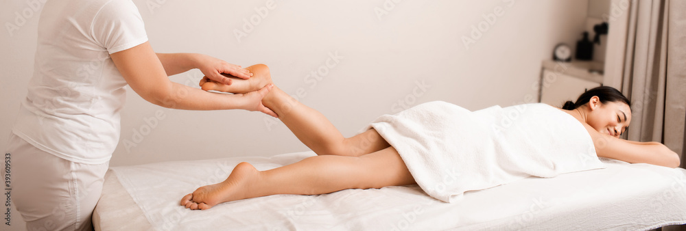 Obraz premium Asian woman receives a foot massage. Therapeutic massage relaxes female foot muscles