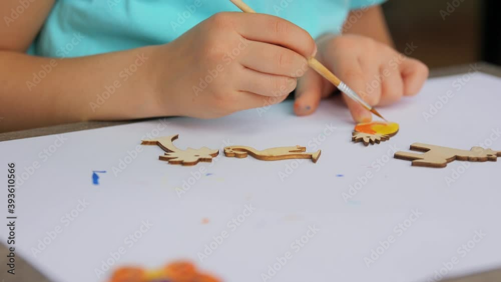 childhood, hobby and leisure concept - hands of little girl with brush painting wooden blanks at home childhood, hobby and leisure concept - hands of little girl with brush painting wooden blanks at home