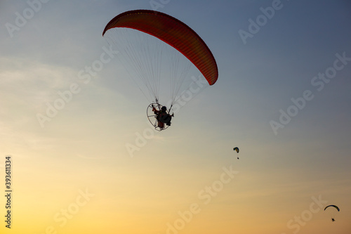 Paragliders flying with a paramotors during beautiful sunset