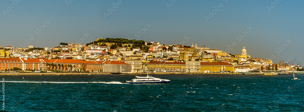 River traffic on the Tagus river, Lisbon, Portugal with a backdrop of  the Commercial Square, Castle Hill and Alfama district