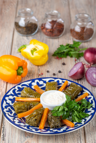 plate with dolma and carrots slices with sour cream on wooden background, close vie