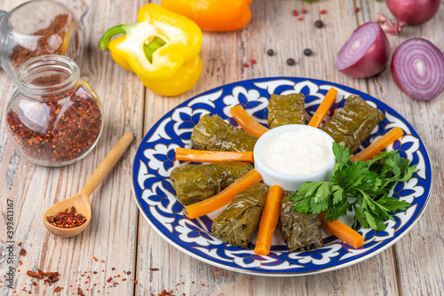 plate with dolma and carrots slices with sour cream on wooden background, close vie