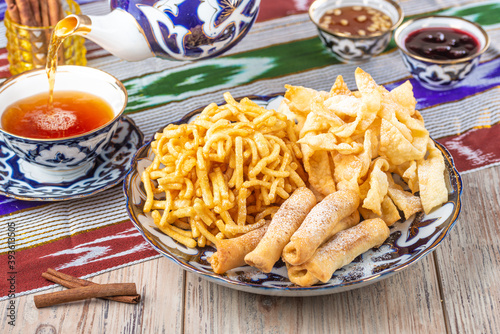 plate with crispy snacks with cup of tea on wooden background, close view, tea time concept 