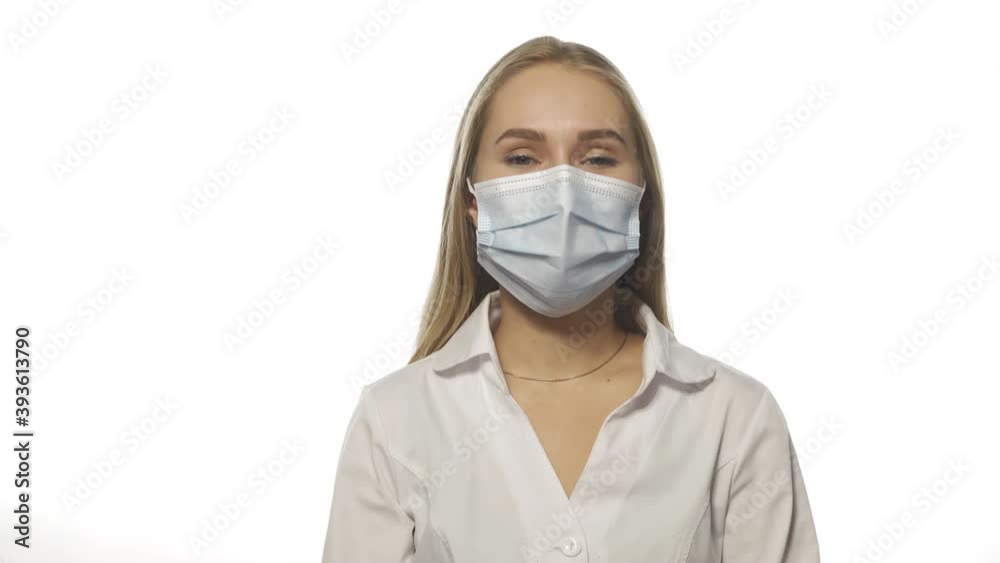 Young blond haired doctor fixing medical mask wearing purple disposable gloves, looking at the camera. Isolated on white background. High quality 4k resolution footage. Young blond haired doctor fixing medical mask wearing purple disposable gloves, looking at the camera. Isolated on white background. High quality 4k resolution footage.