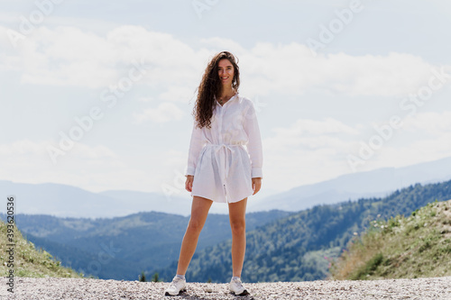 Girl traveler is smiling in the mountains. Attractive woman posing on the green hills background. Advert for travel agency. Tourism © Rabizo Anatolii