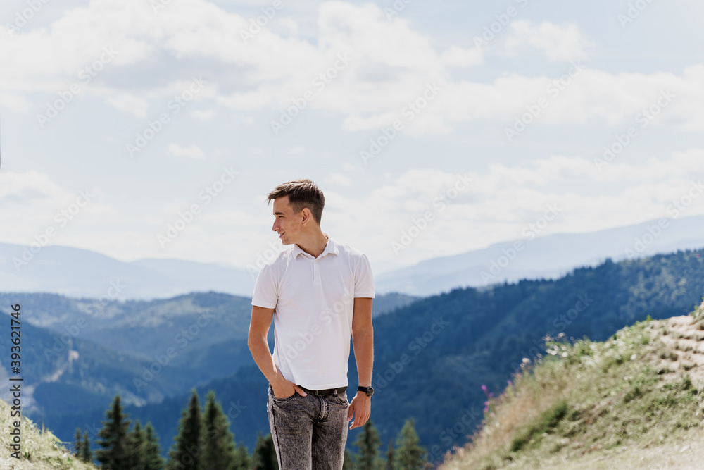 Men traveler is smiling and posing on the green hills background. Advert for travel agency. Tourism. Travelling in the mountains. Men traveler is smiling and posing on the green hills background. Advert for travel agency. Tourism. Travelling in the mountains.