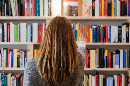 Young blonde woman on her back choosing a book in a bookstore.