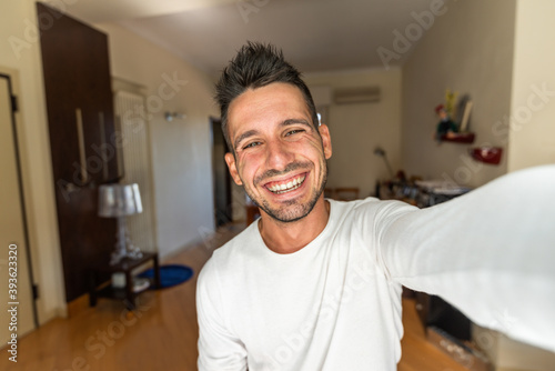 Happy caucasian man smiling at the camera - Young guy taking a selfie at home