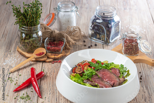 plate with fried cuts of meat and salad with arugula on wooden background, close view 