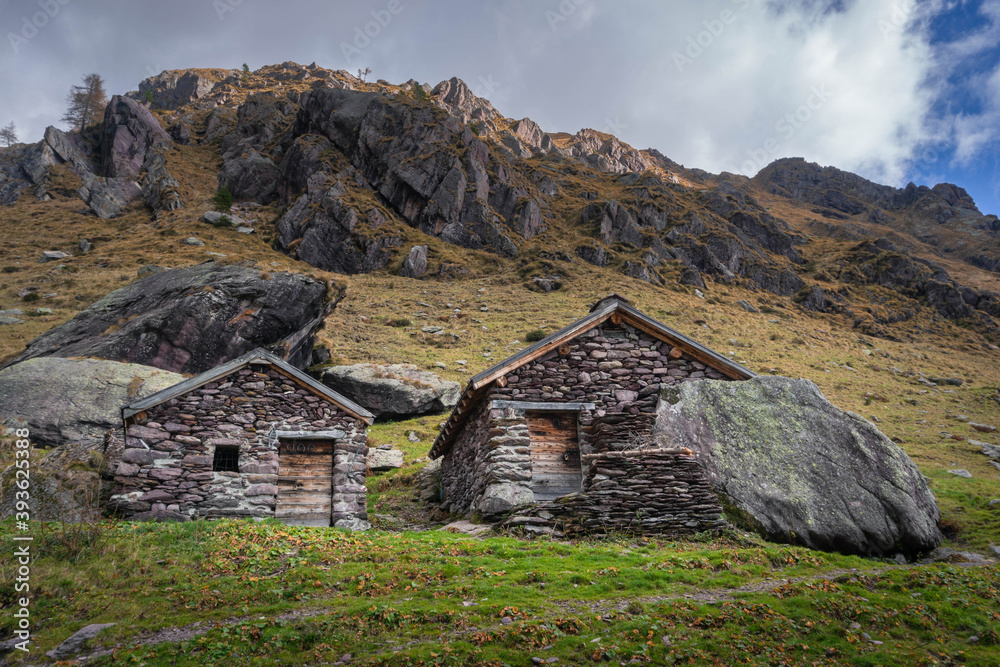 Autumn landscape with two old cabins used as a mountain huts in Valsanguigno - Orobie - Italian Alps