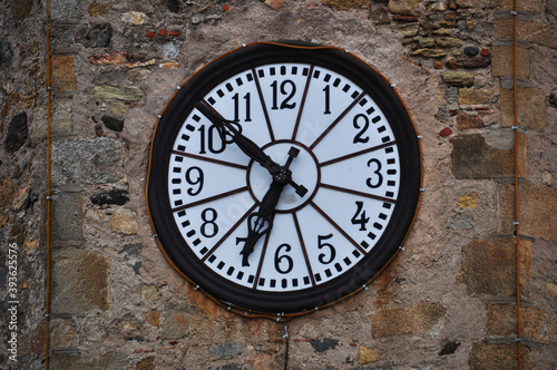 Background, round clock with a light dial on a stone wall