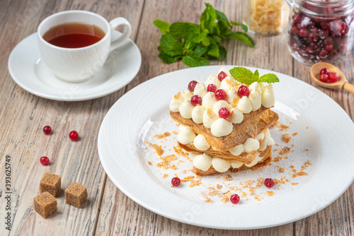 plate with berry dessert and  cup of tea on wooden background, close view 