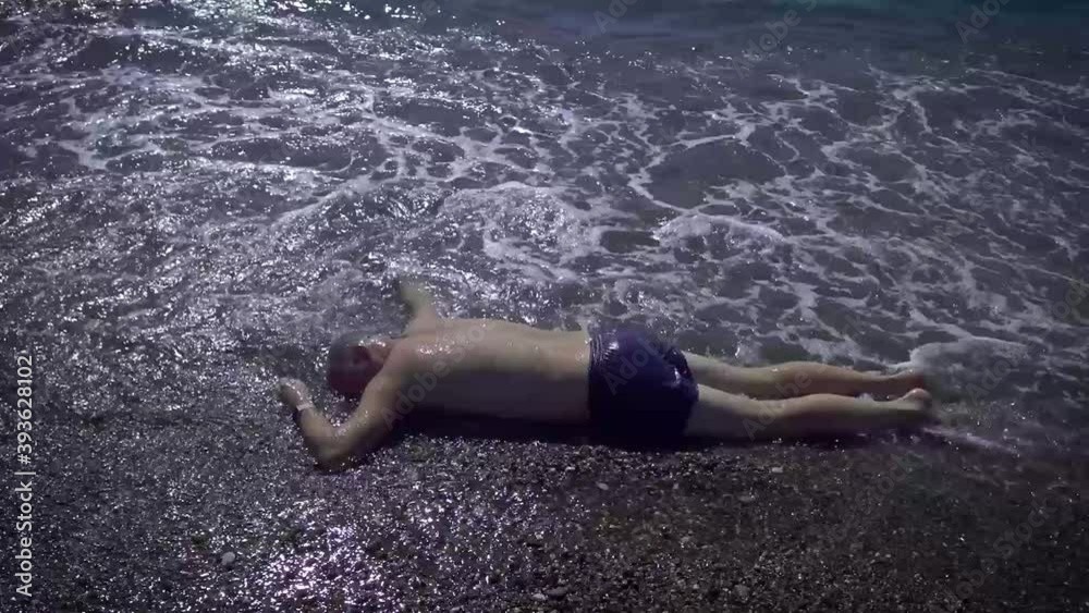 The body of a man washed up on the beach. A drowned man in swimming trunks who was neglected by safety rules on the water.