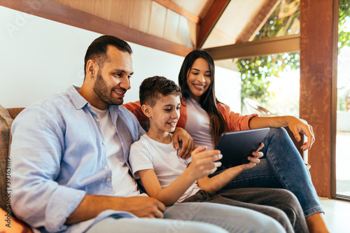 Parents and son using tablet on sofa at home