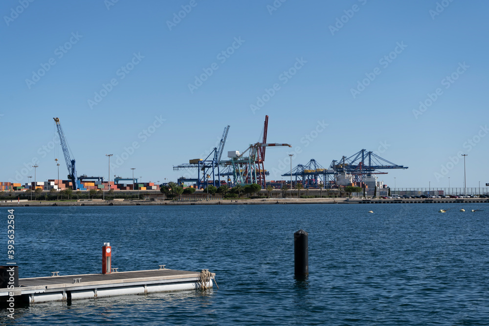 Port of Valencia view with shipping container terminal and cranes.Important harbour in Mediterranean Sea .Industry , transport and business concept background.