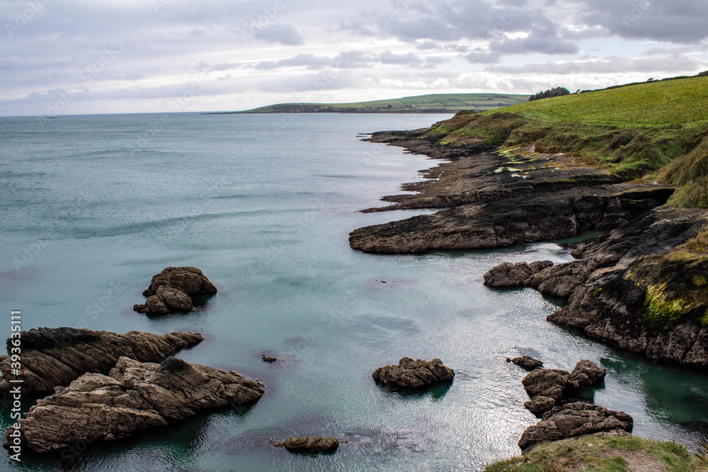 The rocky West Cork coastline with the sunseting and boulders covered in Irish sea moss. The seven heads cliffs are popular with hikers and hill walkers.