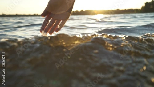 close up woman hand gently touches the surface of the water in the sea