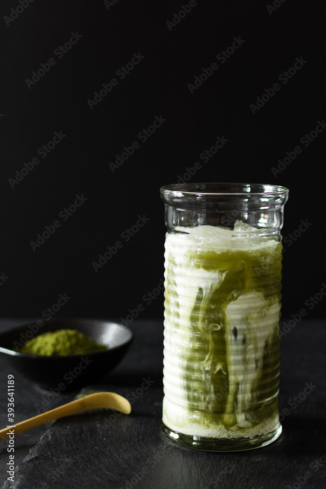Fototapeta premium Green matcha iced latte in a long glass on black background.