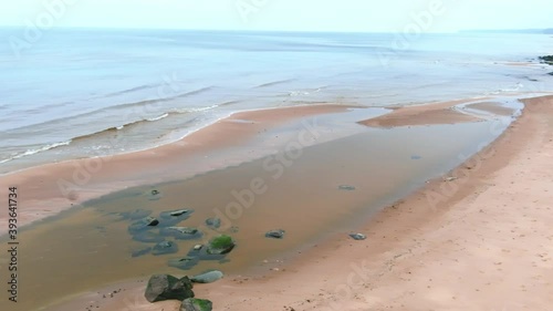 Aerial fly along calm sea, sandy beach with seastones photo