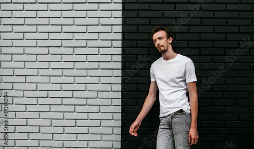 Young bearded hipster guy wearing white blank t-shirt. Mock-up for print. T-shirt template.